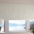Lifestyle of a Mid-Century Modern Living room scene of the Motorized Blackout Roller Shades in the Catania Off-White color with the Fabric Wrapped 4in. Cornice and Inside Mount.