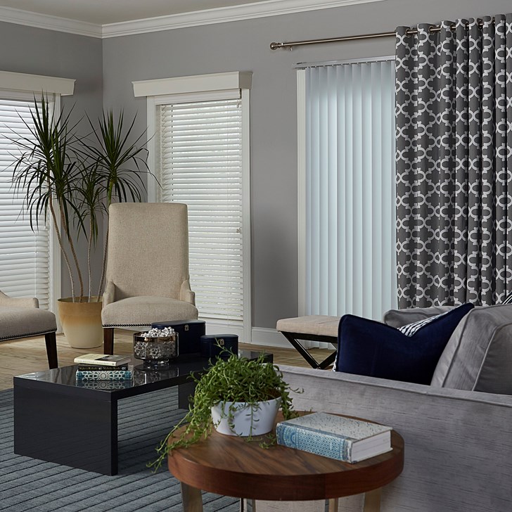 Vinyl Vertical Blinds in the Basic Smooth White color, 2 Inch Wood Blinds in the White color, Wood Cornice in the Davenport Cotton color, and the grommet drapery in Casablanca Mineral color.
